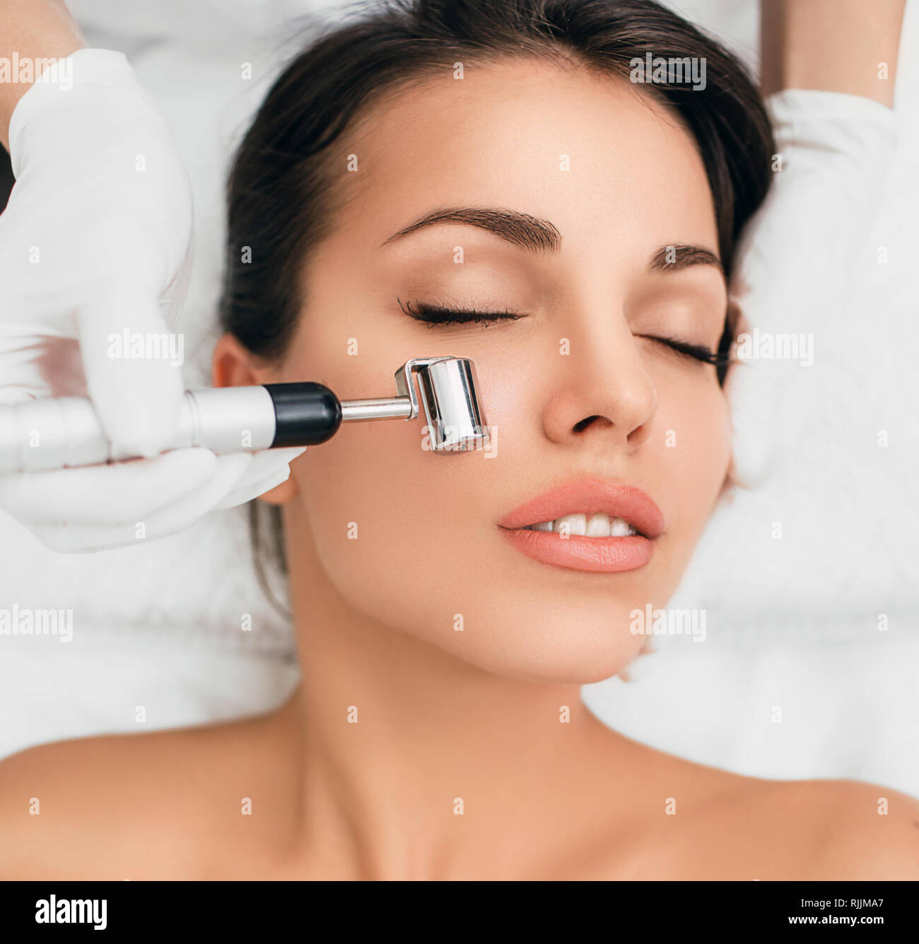 Woman getting procedure facial rejuvenation and lifting with mesotherapy roller Stock Photo