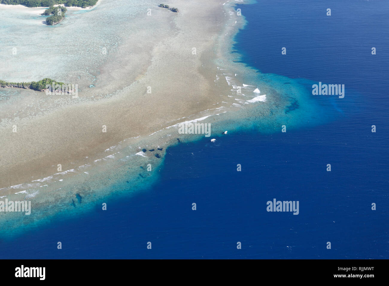 Aerial landscape of sandy beach on tropical islands, shallow coral reefs and 2 boats at Blue Corner Palau Stock Photo