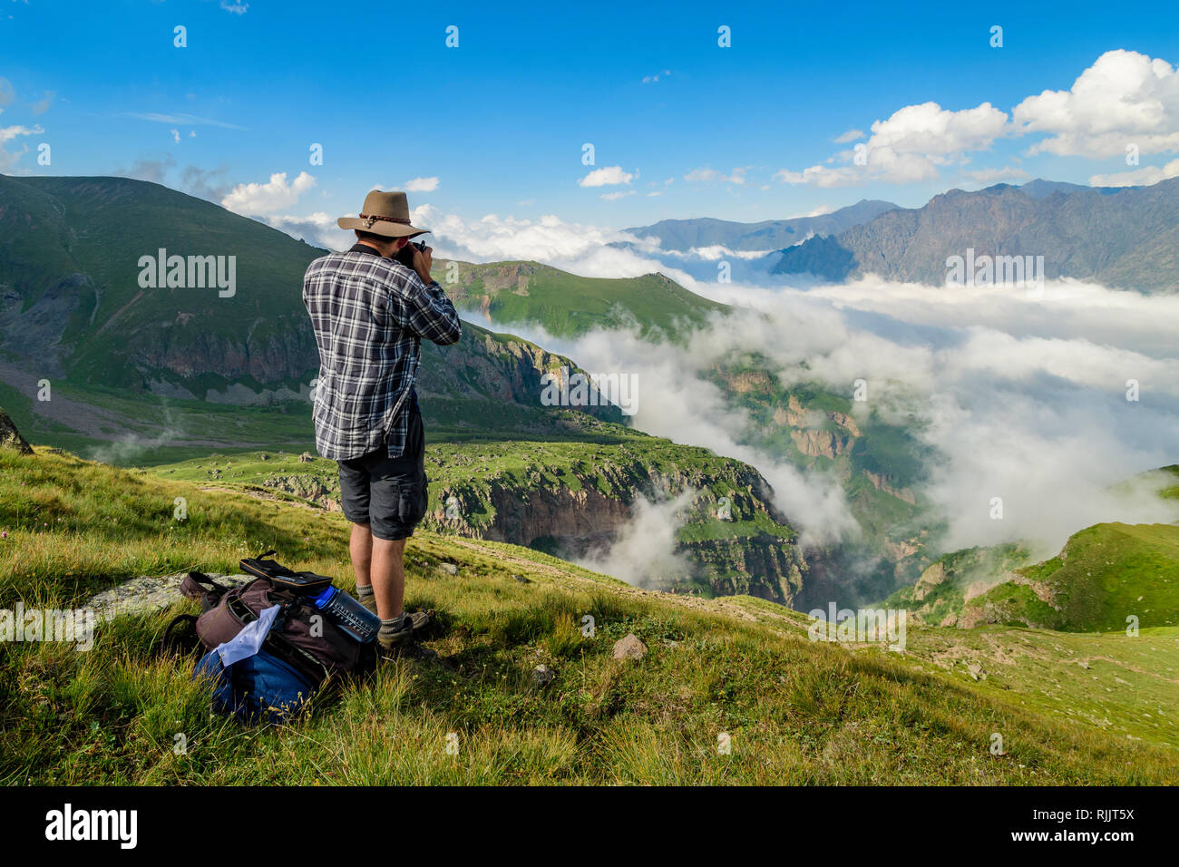 Man taking images of the landscape around Mount Kazbek during a hike. Stepantsminda, Georgia. Stock Photo
