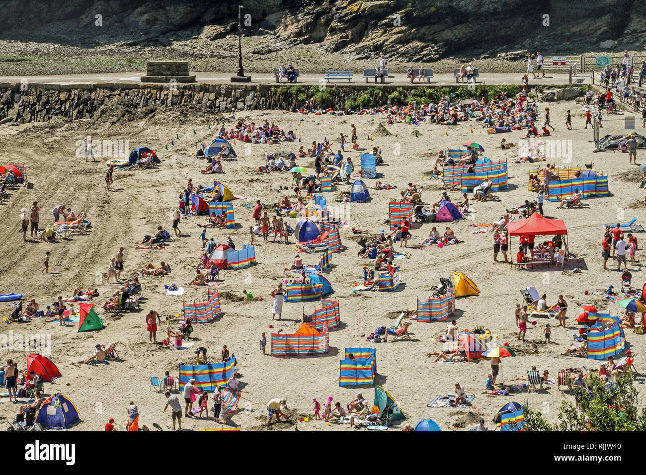 Visitors enjoy the sunshine, sand and sea on the popular beach at East Looe in Cornwall. Stock Photo