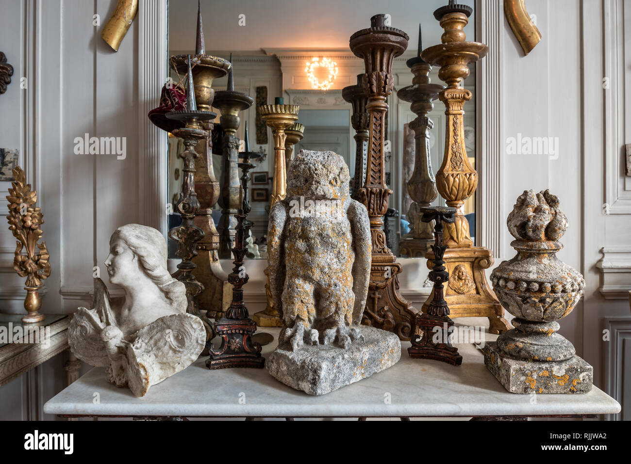 Carved marble angel and stone owl with candlesticks and finial on marble topped table. Stock Photo