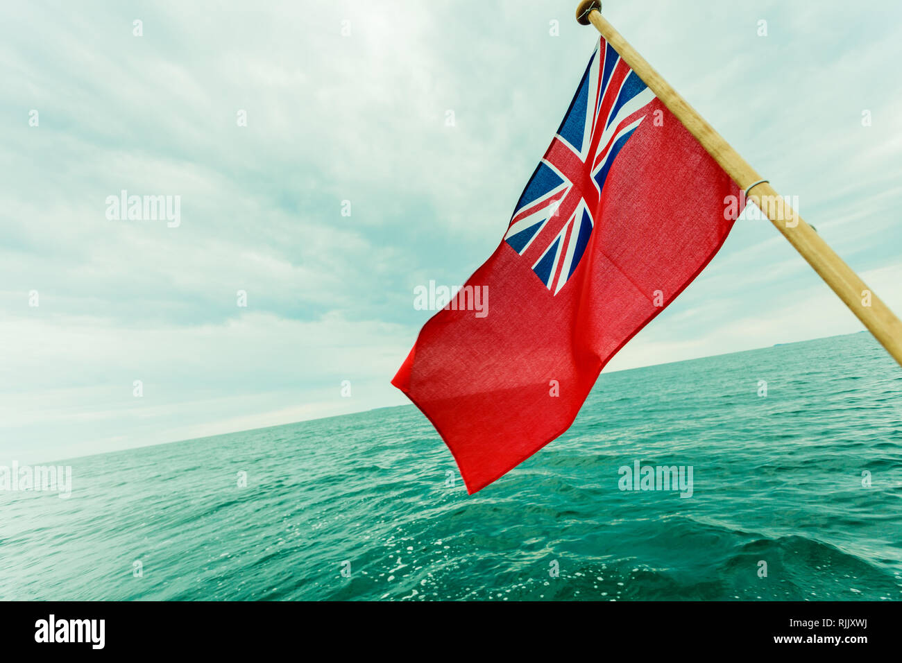 The uk red ensign the british maritime flag flown from yacht sail boat,  blue sky and baltic sea. Summer and travel voyage Stock Photo - Alamy