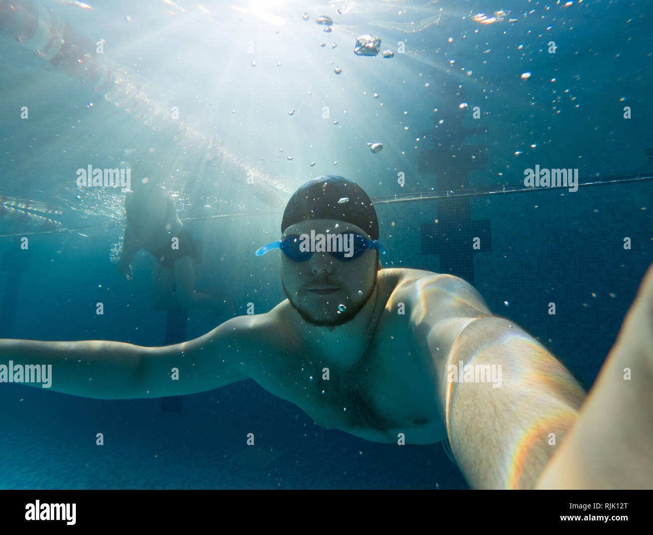 man underwater holding breath in pool. blue goggles Stock Photo Alamy
