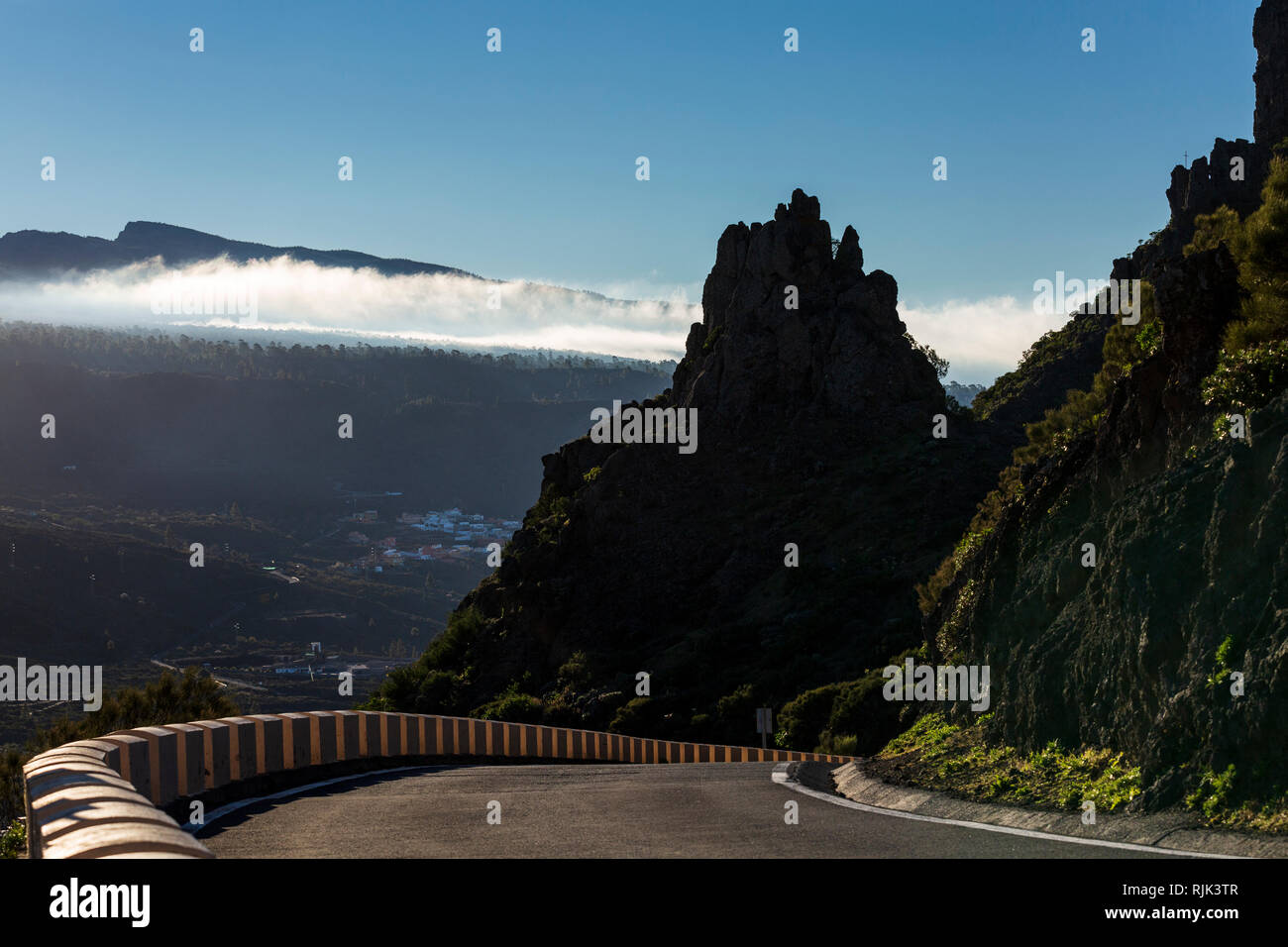 Dawn backlighting clouds and highlighting the road over the ridge between Santiago del Teide and Masca, West Tenerife, Canary Islands, Spain Stock Photo