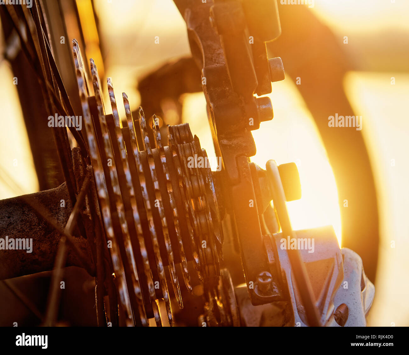 Detail view of a bicycle in a backlit situation, close up on chain and gears, signs of wear show the use on a bicycle tour Stock Photo