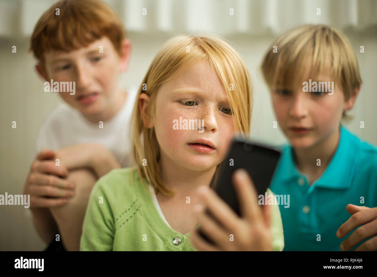 Young siblings using a smart phone. Stock Photo