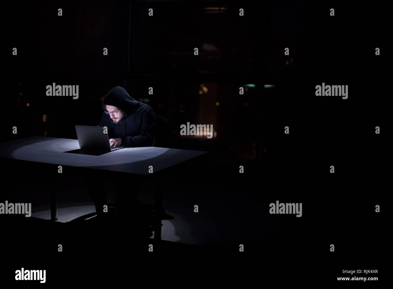Young talented hacker using laptop computer while working in dark ...