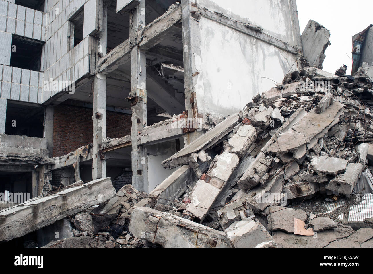 A huge pile of gray concrete debris from piles and stones of the destroyed building. The impact of the destruction. Stock Photo