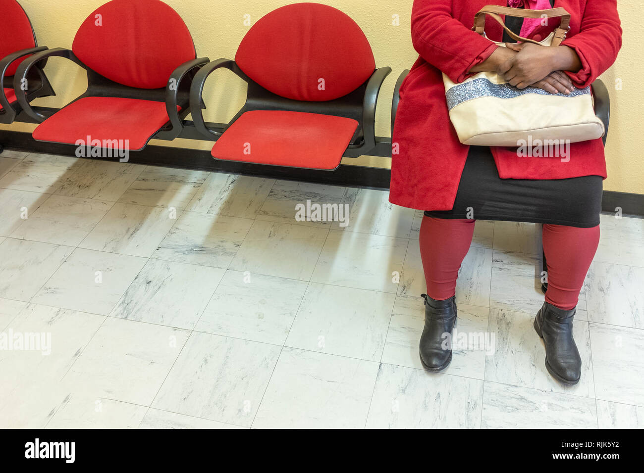 Health care: view of feets of a woman in red in waiting room for doctor's appointment Stock Photo