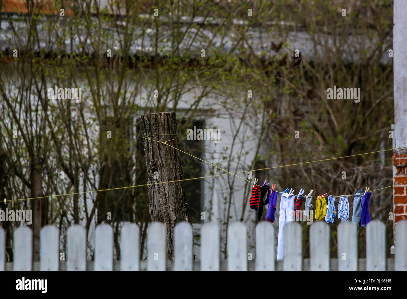 Clothes and clean washed laundry are dried behind the fence. Inner yard with clothes and linen drying on the ropes in Latvia. Colorful clothes laundry Stock Photo