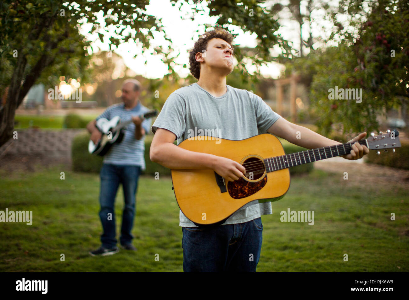 Father and son practicing playing guitar together. Stock Photo