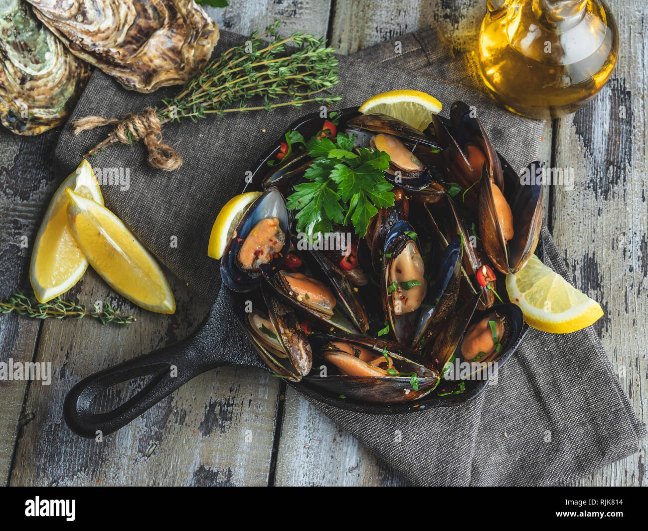 Cooked seafood clams mussels in the iron pan portion with lemon and seasoning Stock Photo