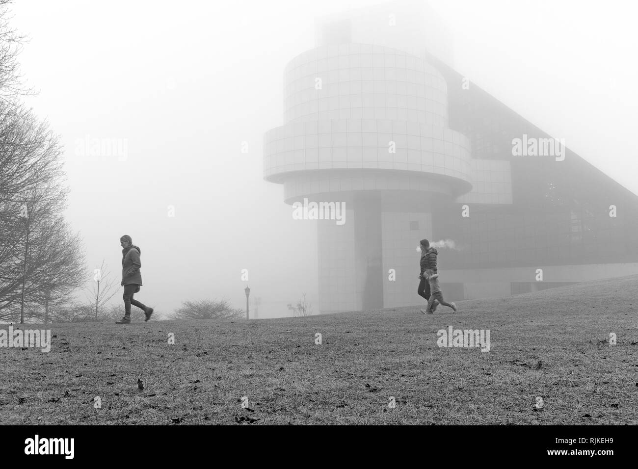 Cleveland, Ohio, USA. 6th Feb, 2019.  Three females cross fog shrouded greenspace next to the Cleveland Rock and Roll Hall of Fame and Museum along the North Coast Harbor in Cleveland, Ohio, USA. Credit: Mark Kanning/Alamy Live News. Stock Photo