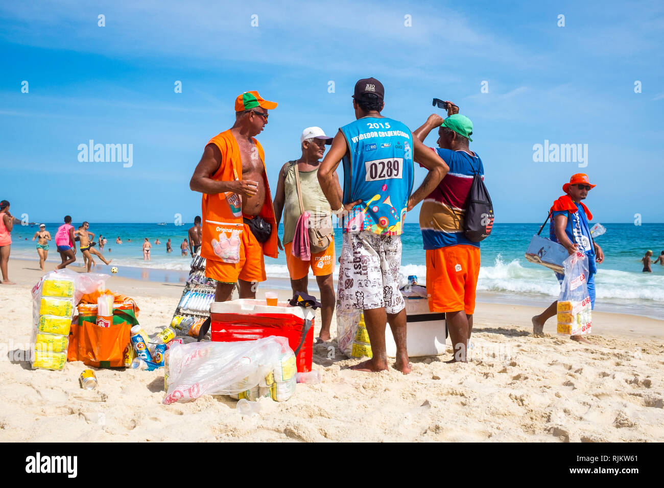 RIO DE JANEIRO - FEBRUARY, 2016: A group of Brazilian beach vendors stand together on the shore of Ipanema Beach, taking a break from walking in heat. Stock Photo