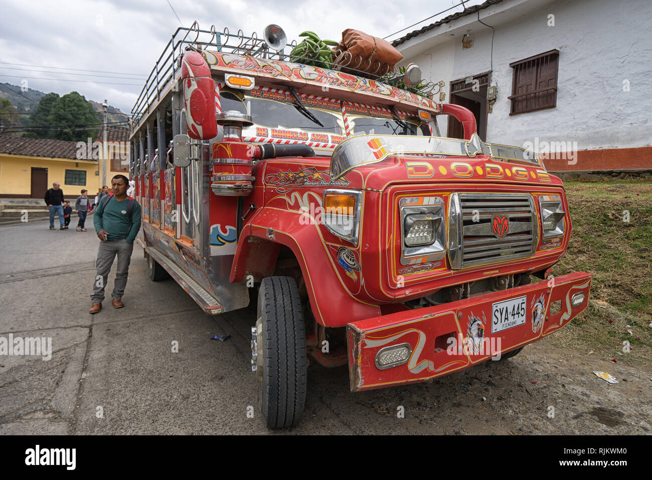 Silvia, Colombia - September 11, 2018: man standing by an old colurful school bus converted to public transportation Stock Photo