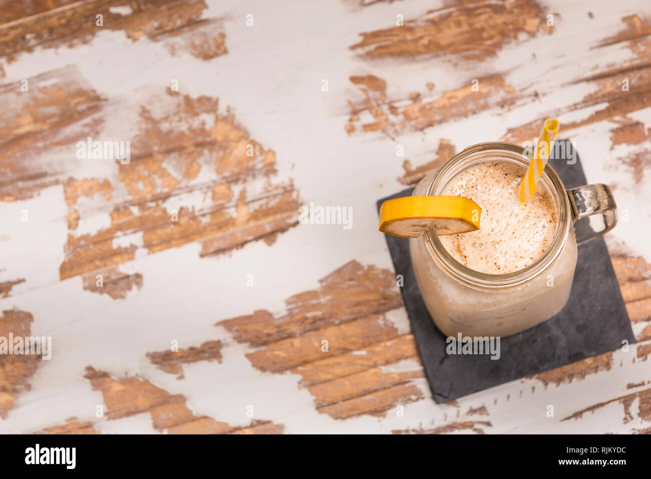 From above tasty fresh drink in glass mug with plastic tube and slice of fruit on coaster on wood table Stock Photo