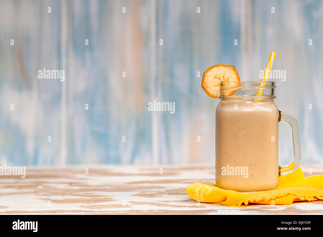 https://c8.alamy.com/comp/RJKYDP/tasty-fresh-drink-in-glass-mug-with-plastic-tube-and-slices-of-banana-on-napkin-on-wood-table-RJKYDP.jpg