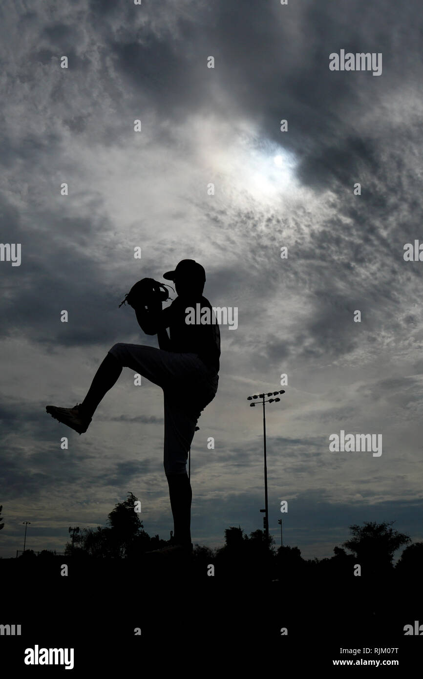 A silhouette of a baseball pitcher pitching off the mound. Stock Photo