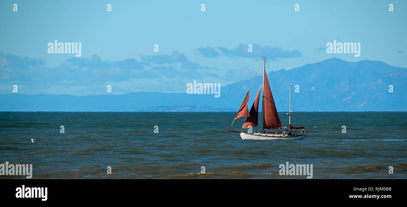 Sailboat with red sail in the Santa Barbara channel on the gold coast