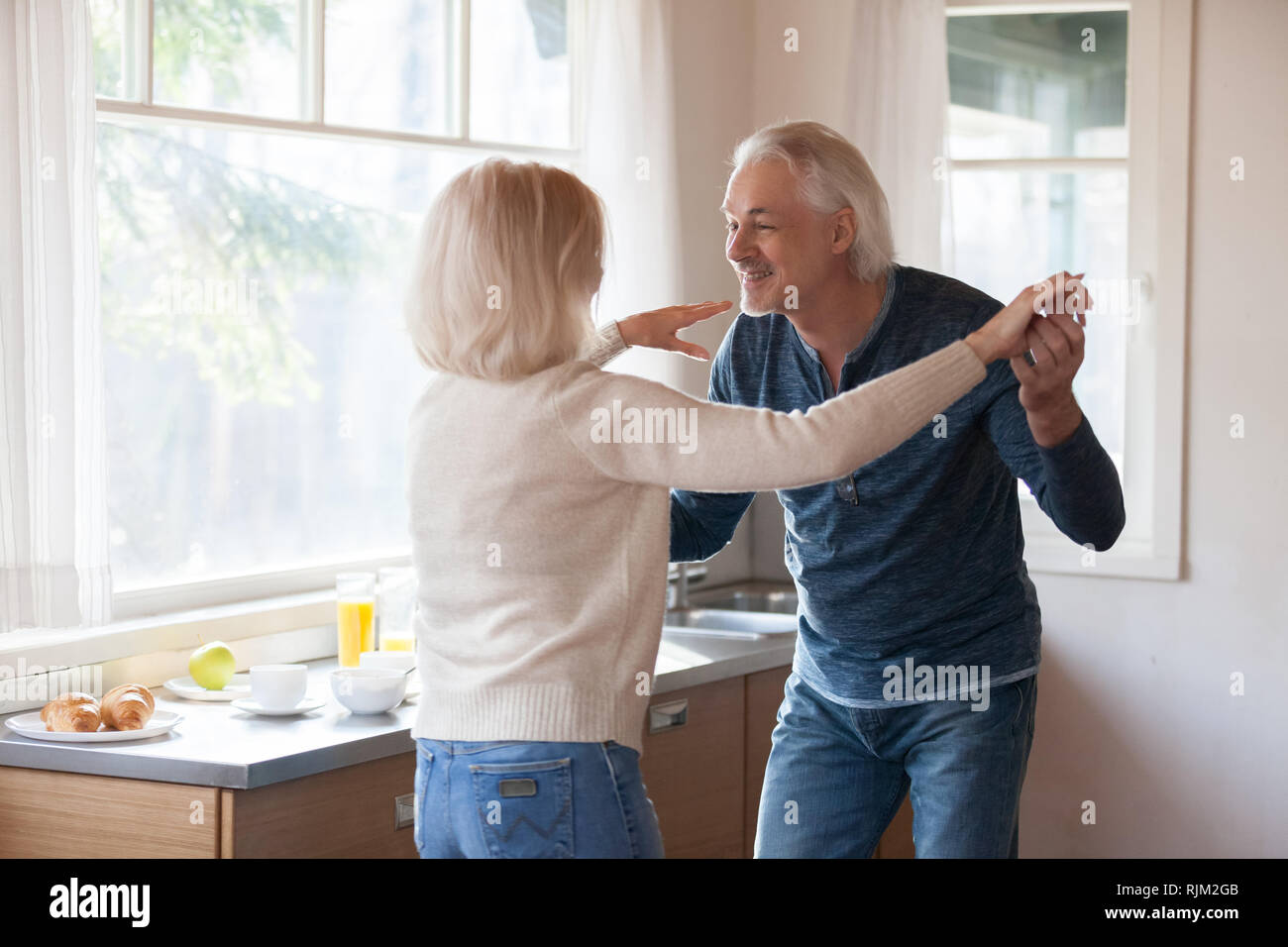 Loving senior couple husband and wife dancing in the kitchen Stock Photo