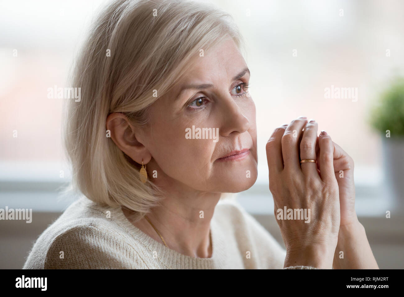 Portrait of sad woman cogitating sitting at home alone Stock Photo