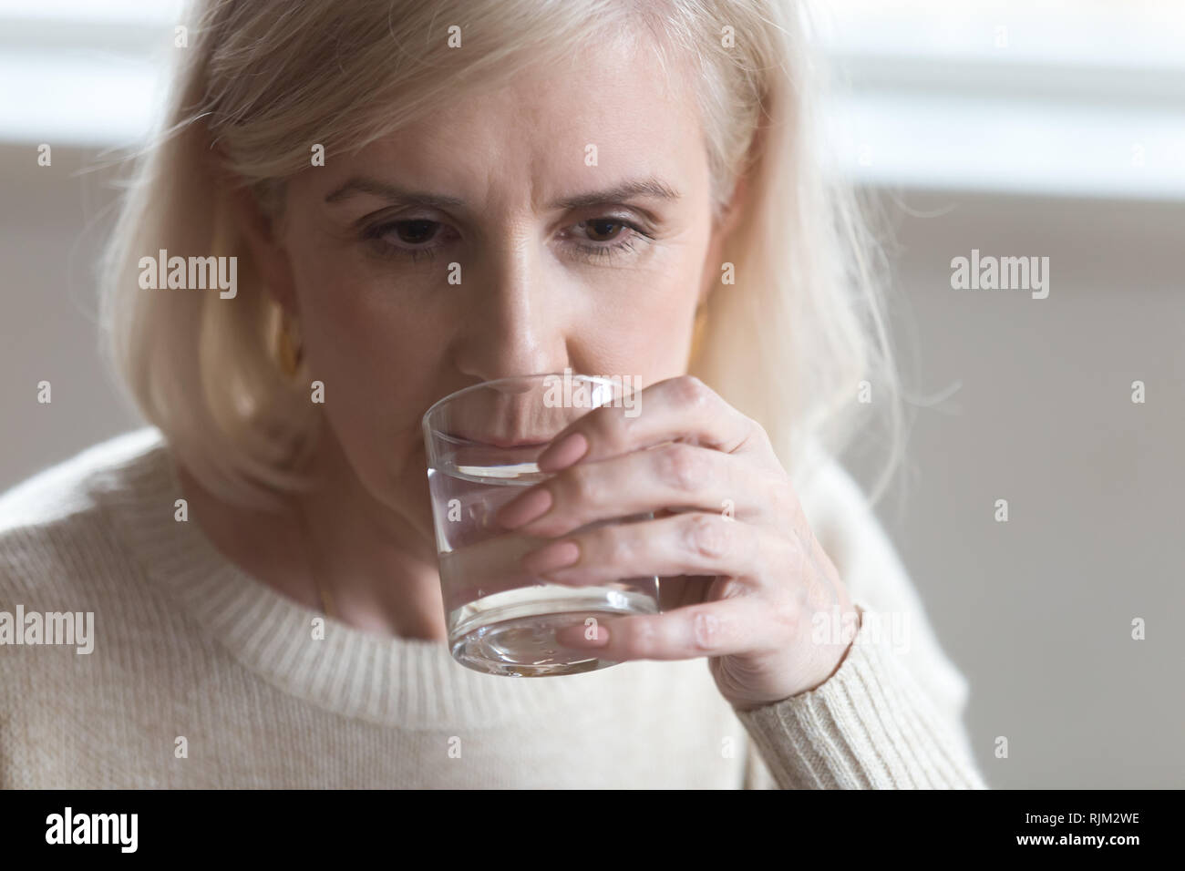 Close up portrait aged woman drinking still water Stock Photo
