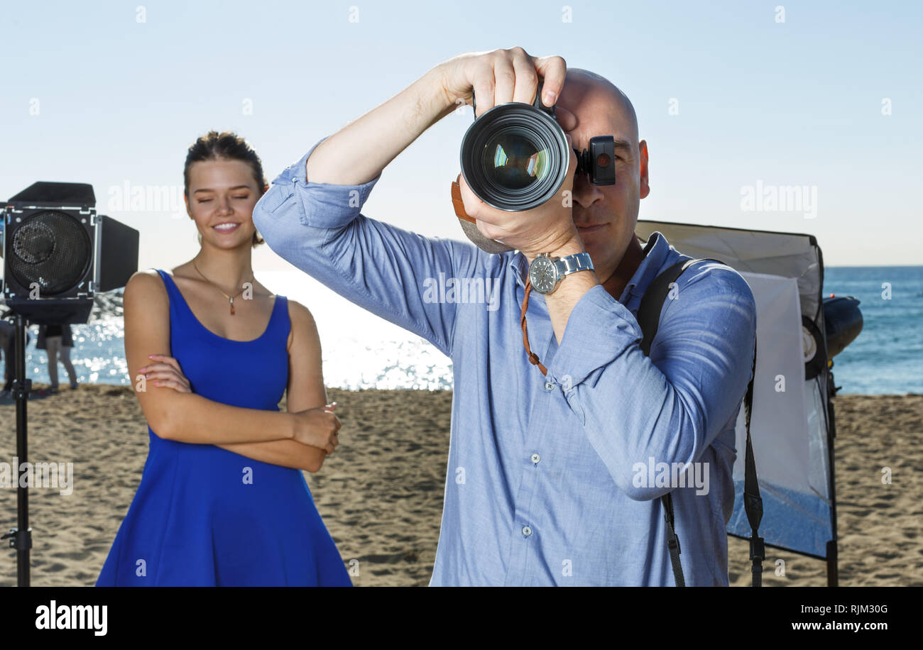 Male photographer with large professional camera looking into