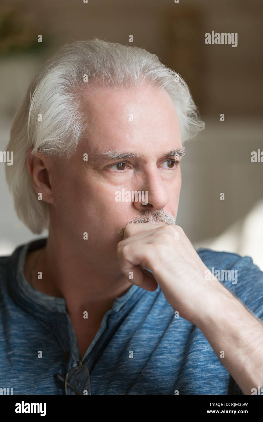Focused puzzled grey haired man at home Stock Photo