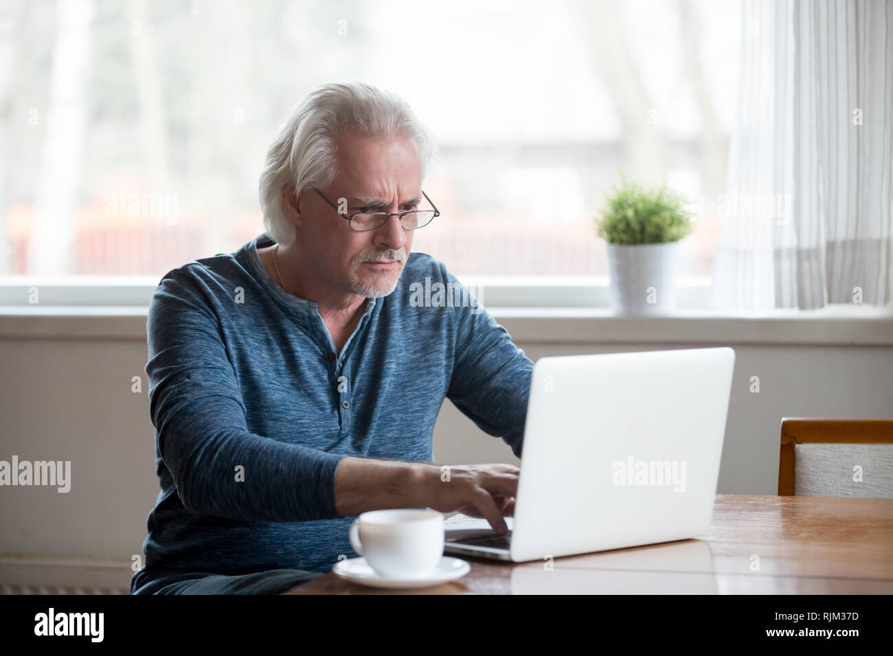 Serious mature man working on computer at home Stock Photo