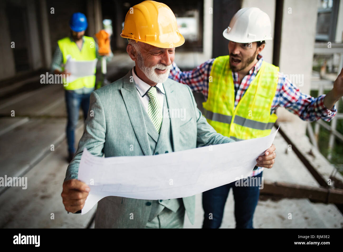 Engineer, foreman and worker discussing in building construction site Stock Photo