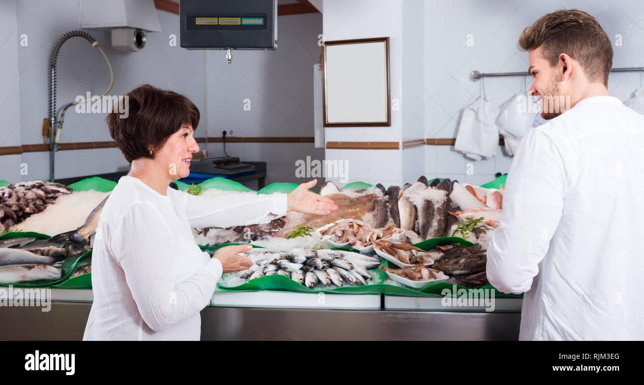 Positive customers choosing seafood in fish store and smiling Stock ...