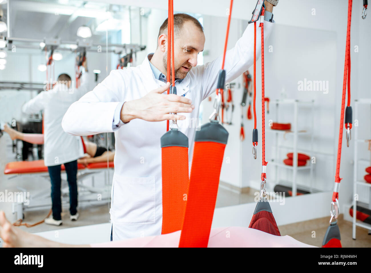 Senior physiotherapist doing treatment to a young woman with spine ...