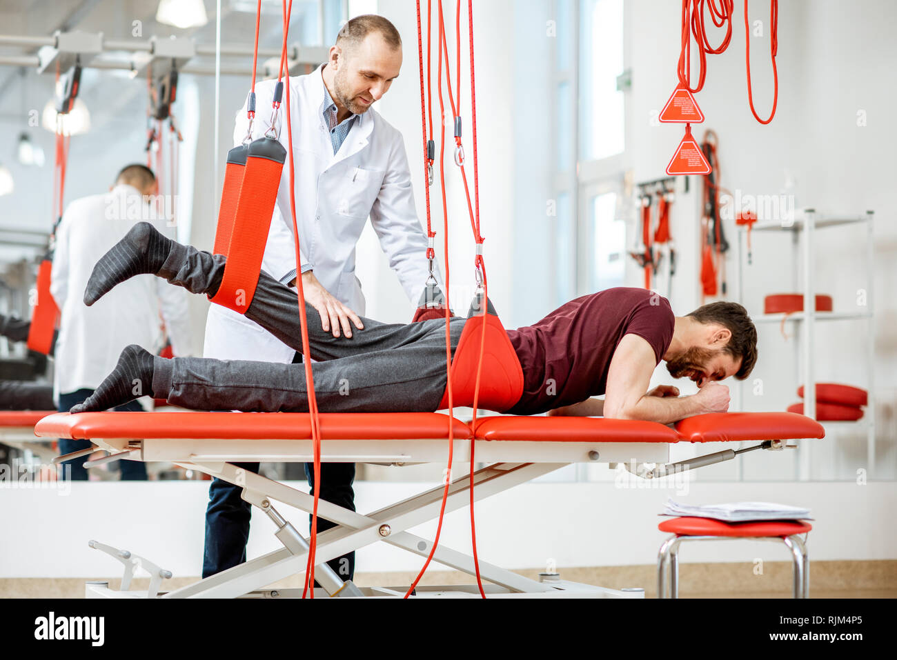 Senior physiotherapist doing treatment to a man with spine problems ...