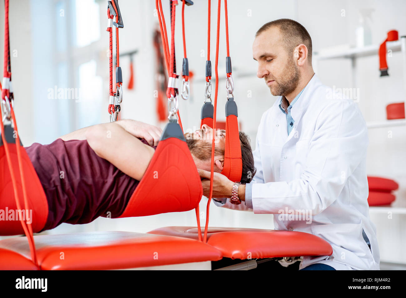 Senior physiotherapist doing treatment to a man with spine problems ...