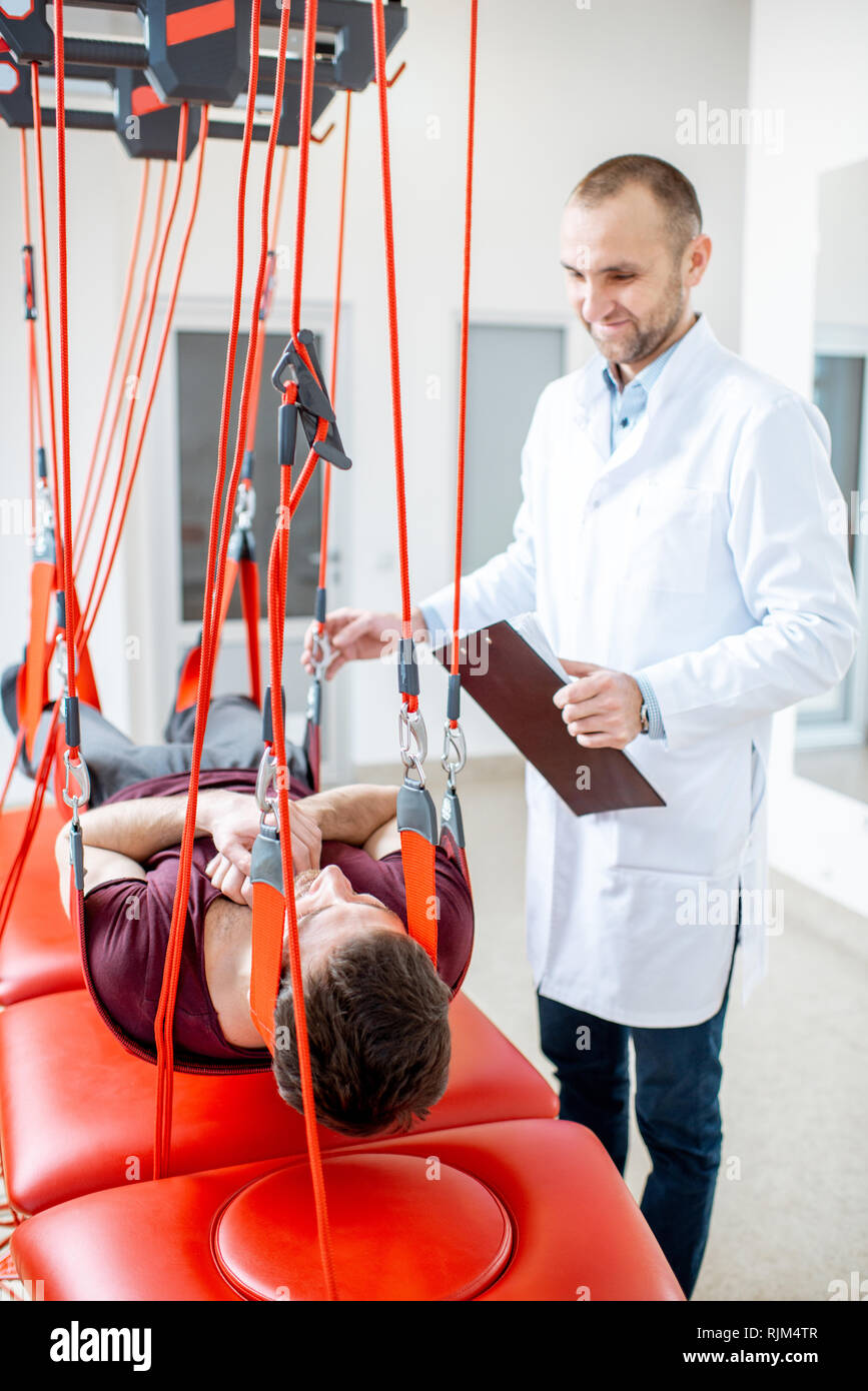 Senior physiotherapist doing treatment to a man with spine problems ...