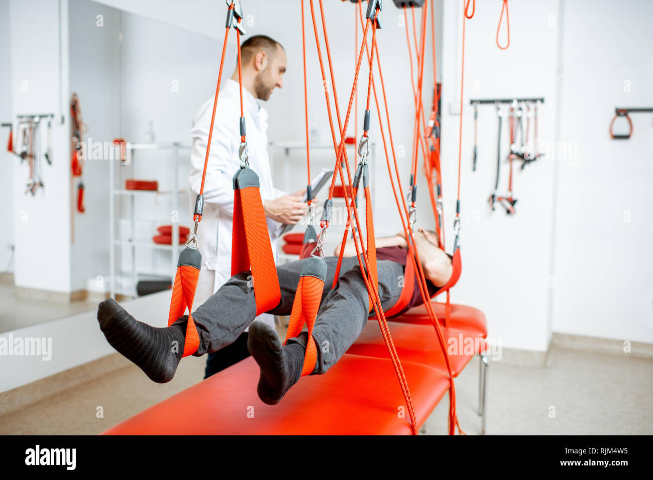 Senior physiotherapist doing treatment to a man with spine problems ...
