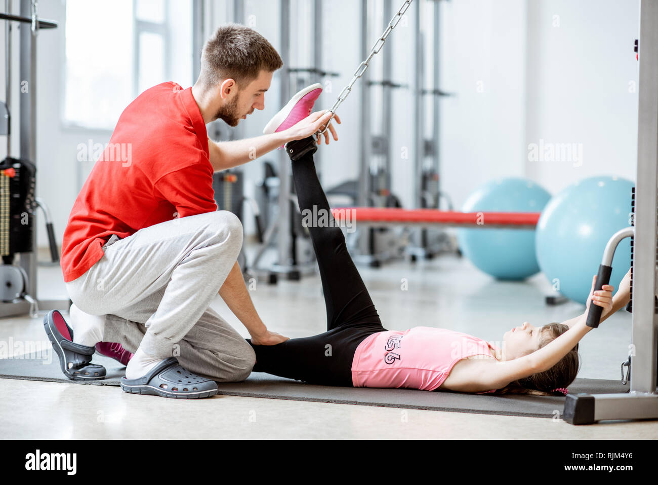 Young girl exercising on the decompression simulators with trainer during the spine treatment at the rehabilitation gym Stock Photo