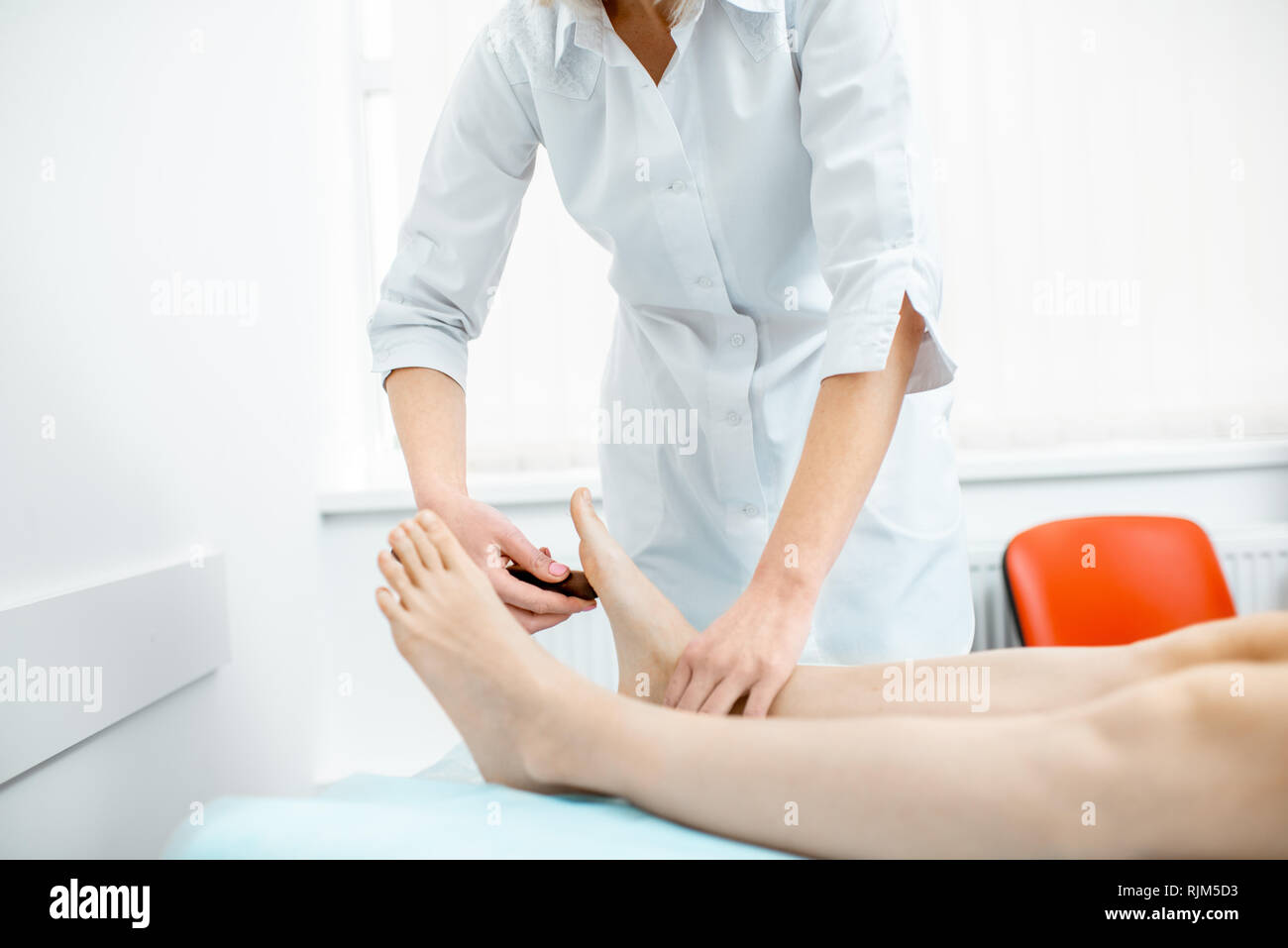 Young woman during the medical examination with neurologist testing reflexes in the office Stock Photo