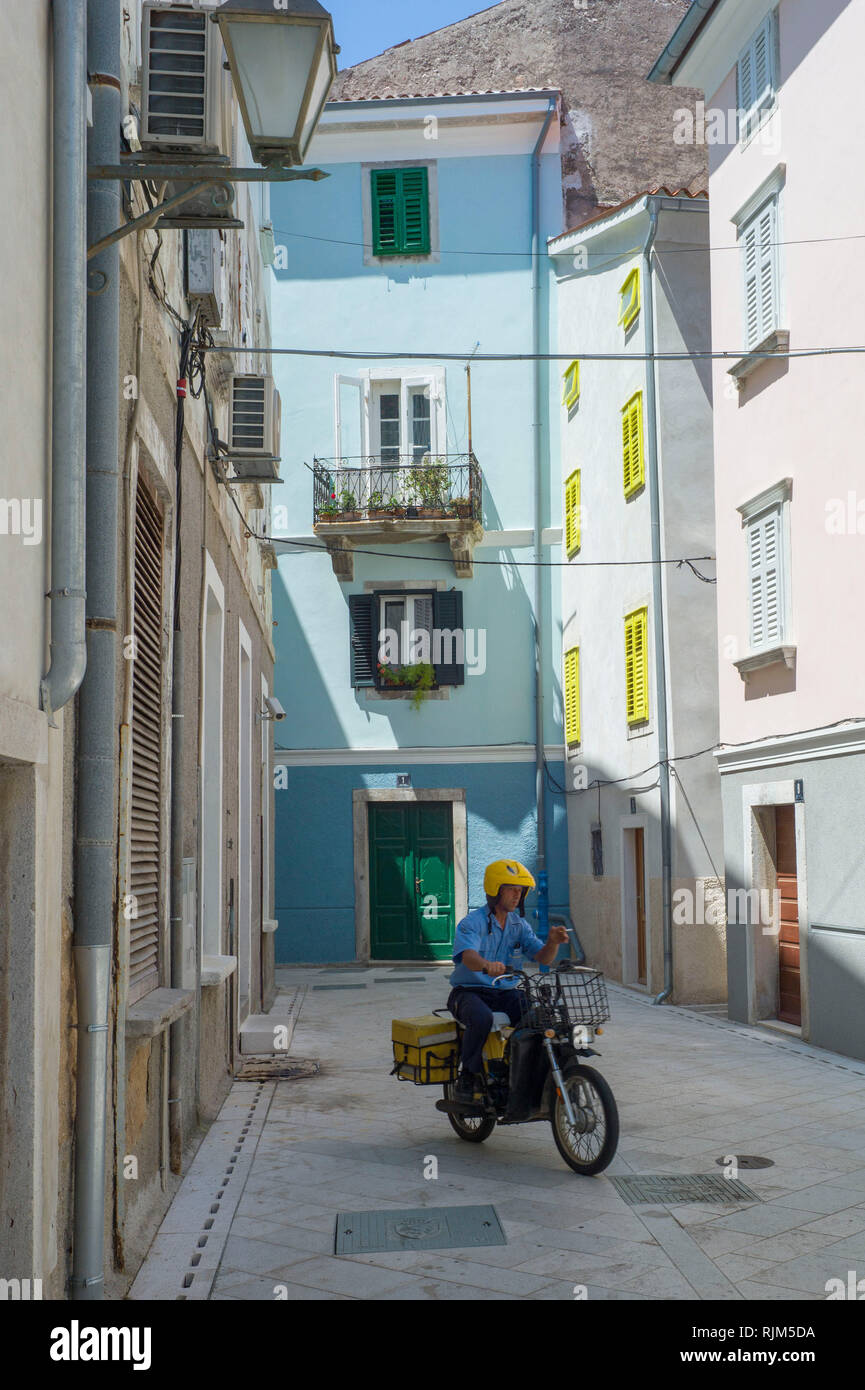 Postman on his motorbike in the town of Cres on Cres Island, Croatia Stock Photo