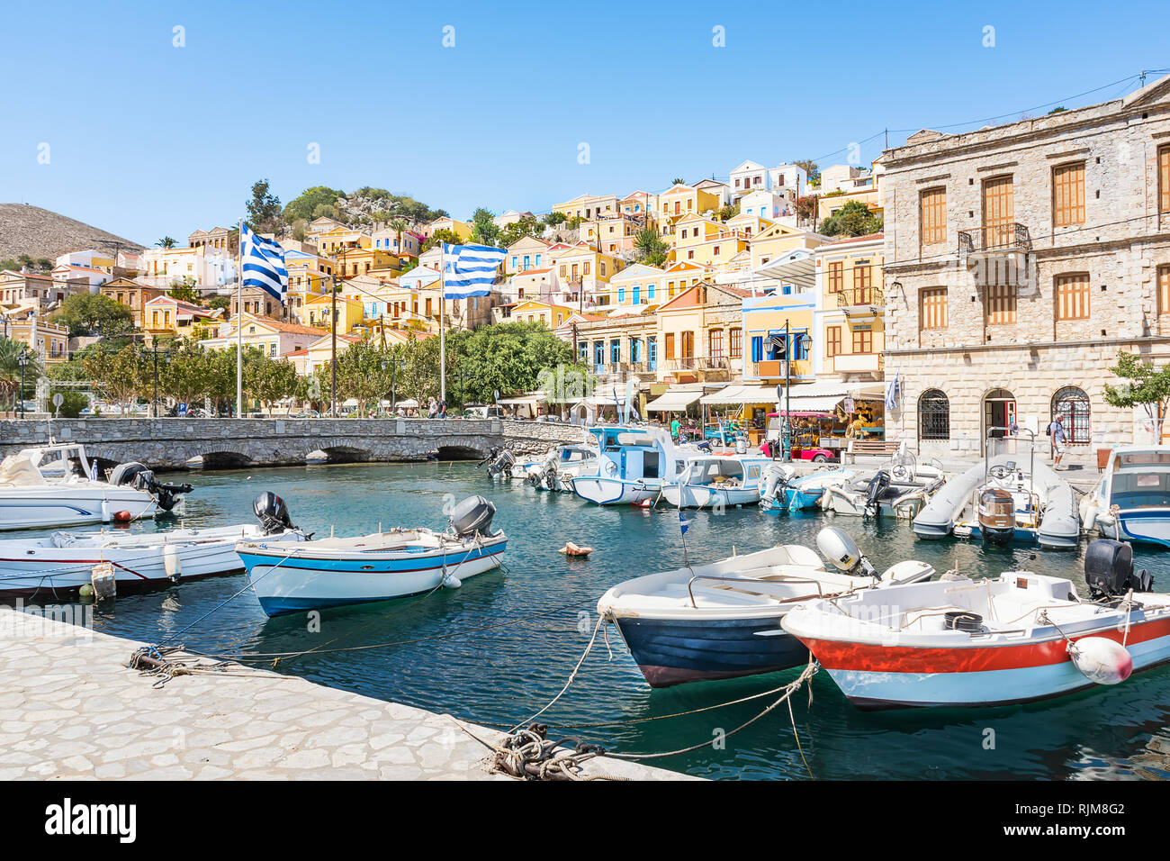 Greek flags, boats and colorful neoclassical houses in harbor town of