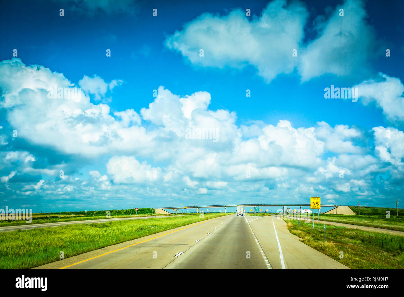 Driving down that long, lonesome highway with endless big sky and clouds in flat landscape of Texas Stock Photo