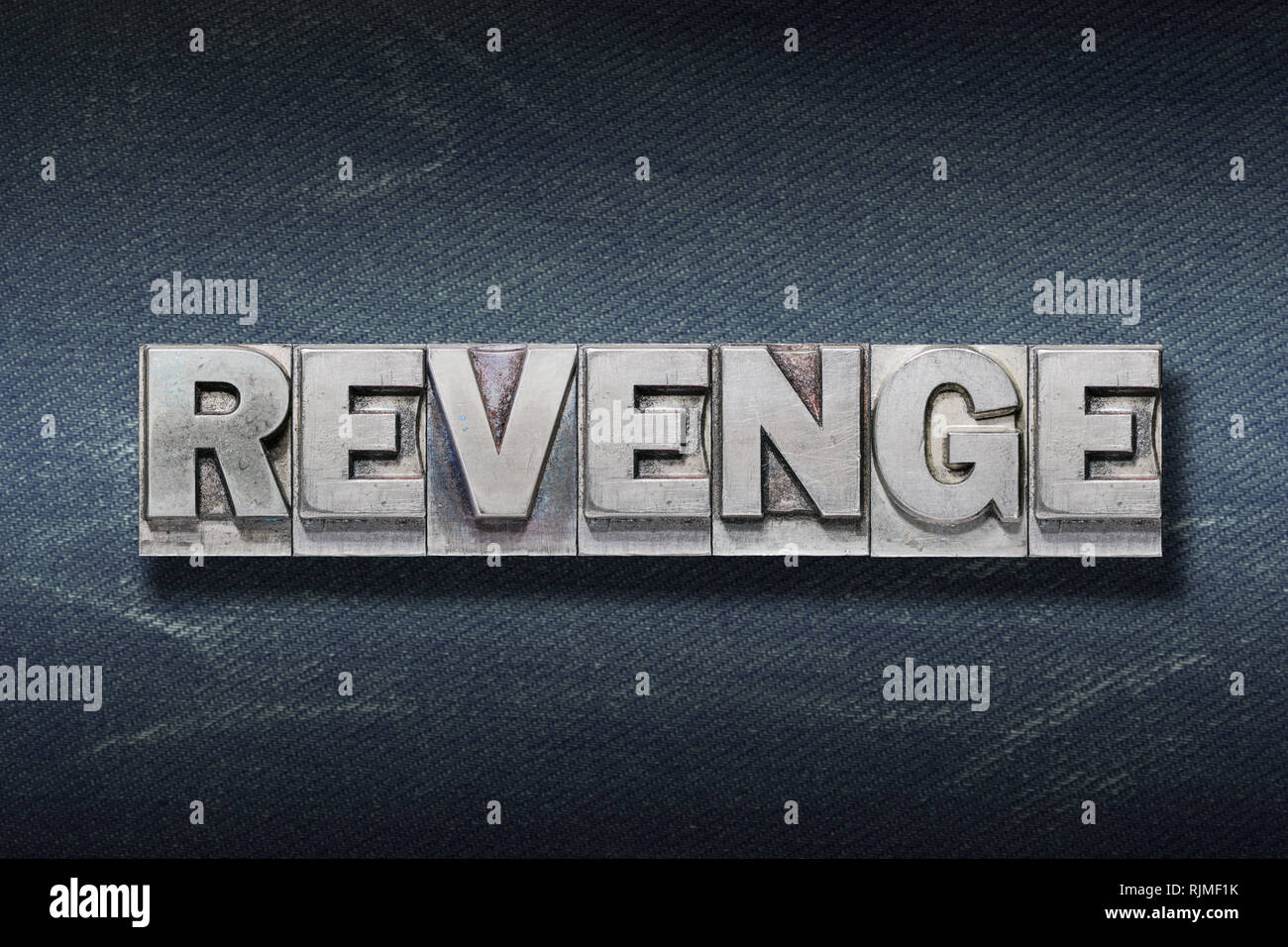 revenge word made from metallic letterpress on dark jeans background Stock Photo