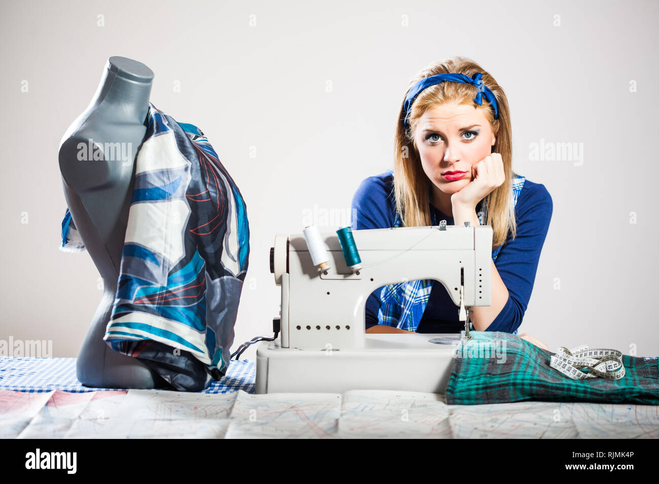Tailor sews and getting bored Stock Photo
