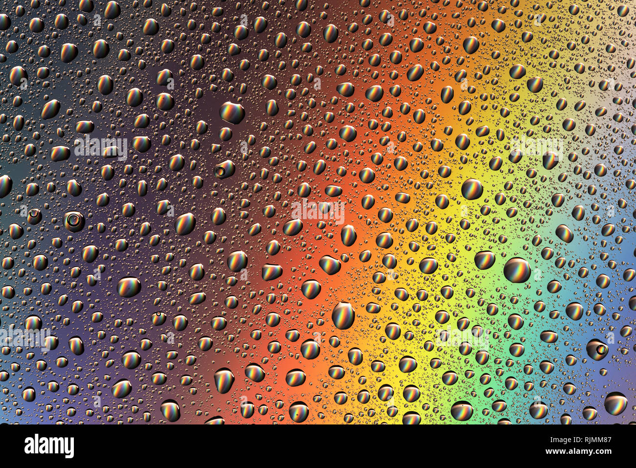 Drops of water on the glass in the light of the rainbow. Abstraction. Background. Stock Photo