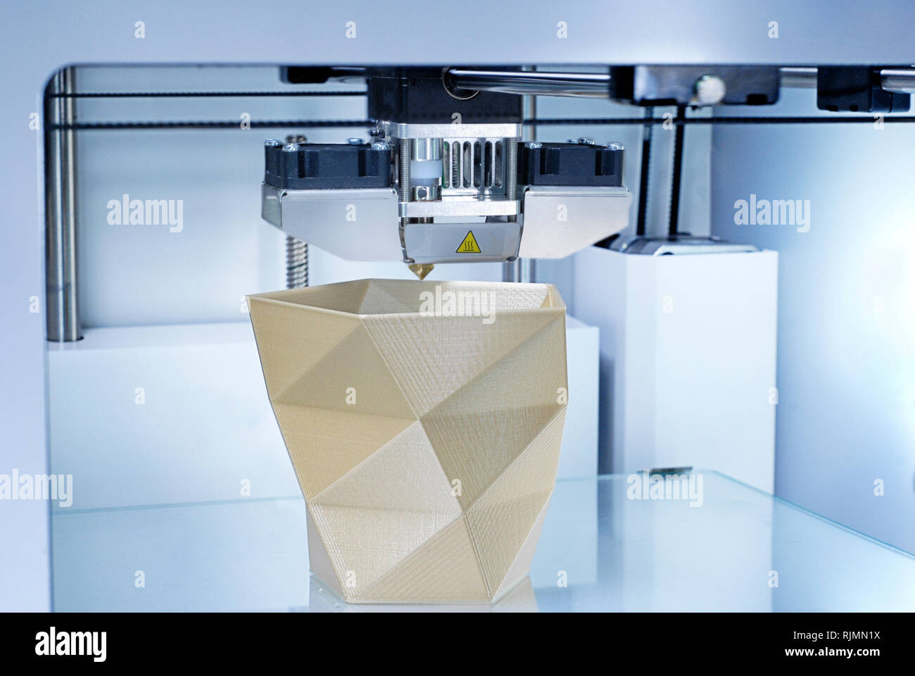 3D Printer producing a Vase from golden PLA (Polylatic Acid) with additive manufacturing technique. Symbol for Future Project Industry or Industry 4.0 Stock Photo