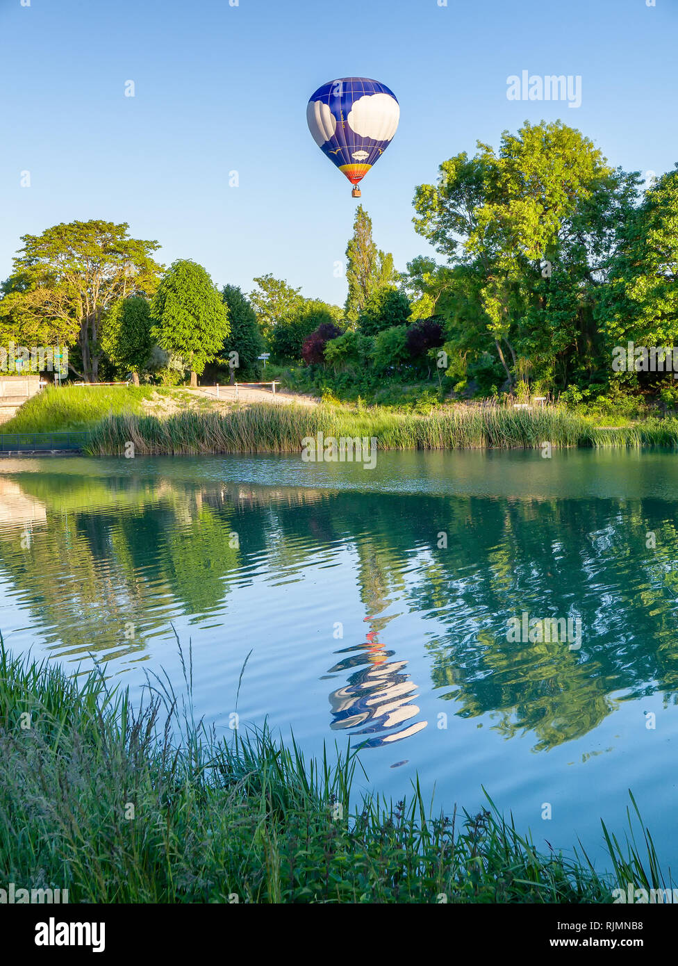 A hot air balloon flying beside the River Marne and reflected in it.  This is near the the village of Mareuil-sur-Ay in the Champagne Region of France Stock Photo
