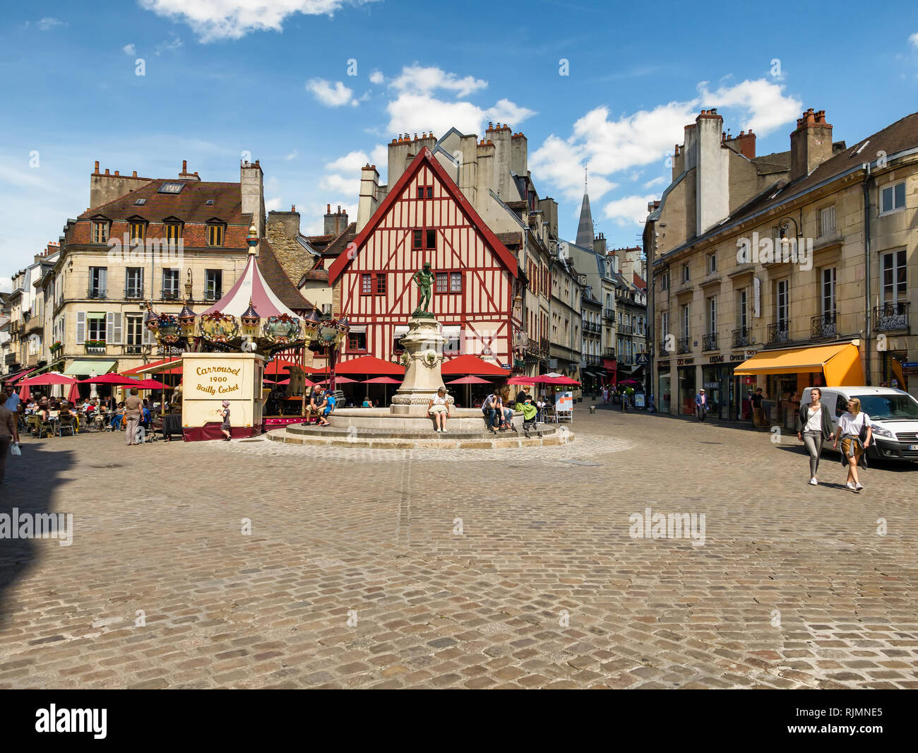 The Place Francois Rude, Dijon, Burgundy, France showing the fountain and the pretty cafe. Also a French merry go round or carrousel in the square. Stock Photo