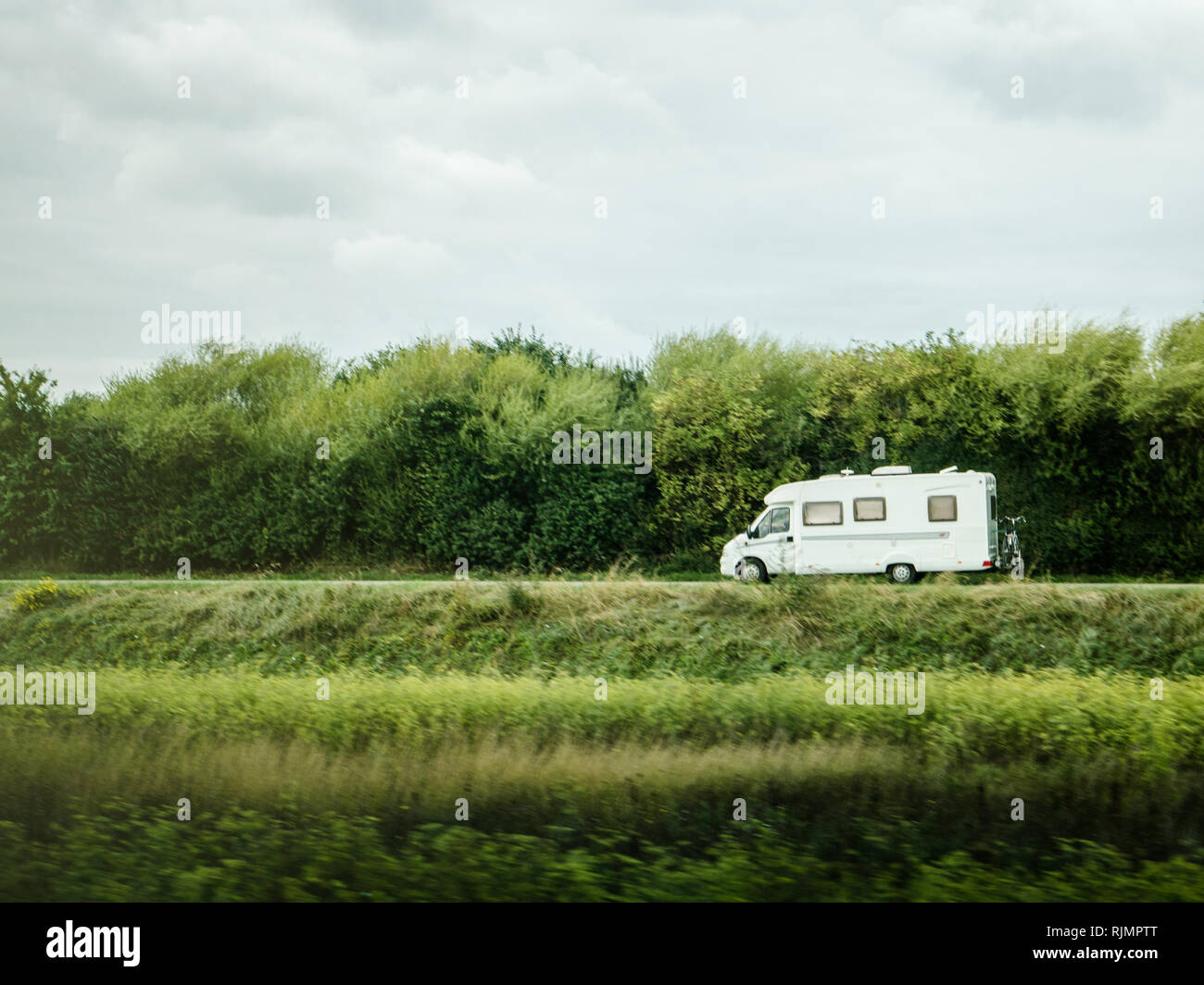 Fast RV camer van driving on the green dunes in Netheralnds during Euroeapn holidays - drive to the left Stock Photo