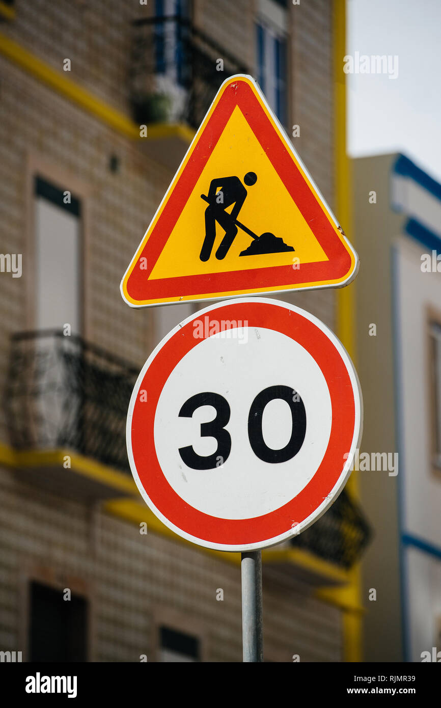 Round signage of with speed limit and triangle sign showing road repair works in sunlight Stock Photo