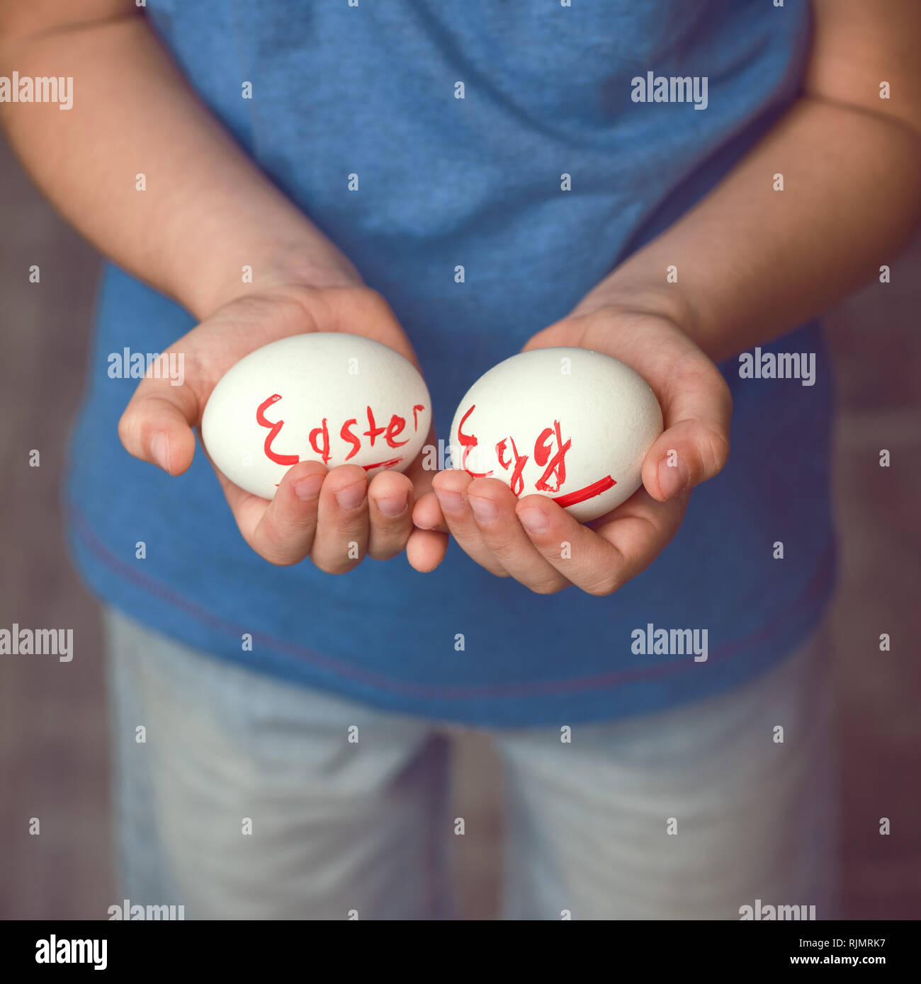 Eggs with the inscription Happy Easter the child holds in her hands in front of him. Stock Photo